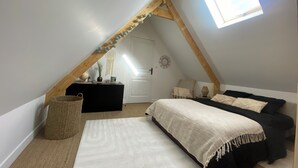 A cozy attic bedroom with a sloped ceiling, a small window, a bed, a chair, and a dresser. - Maison 2 à 6 Pers - En Plein Coeur de la Capitale du lin ! (Yvecrique)