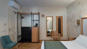 A hotel room with a bed, a chair, a wardrobe, a mirror, and a small table.