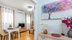 A modern living room with a TV, dining table, chairs, and a decorative painting. - Jesús Gran Poder A. 2 bedrooms (Sevilla)