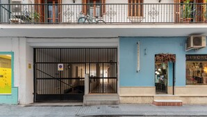 A building with a closed metal gate, a blue storefront, and a staircase leading to an upper floor. - Jesús Gran Poder A. 2 bedrooms (Sevilla)