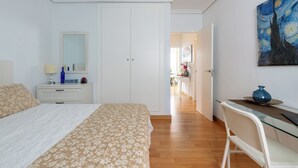 A bedroom with a bed, a desk, a chair, a dresser, a mirror, and a painting on the wall. - Jesús Gran Poder A. 2 bedrooms (Sevilla)