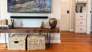 A room with a wooden bench, a painting, a vase, and storage baskets.