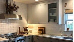 A modern kitchen with white cabinets, a gas stove, and a built-in oven.