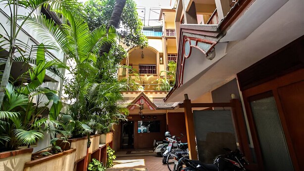 A courtyard with potted plants, a motorcycle, and a building with a balcony. - Hotel Telehaus Lalbagh Botanical Garden (Bengaluru)