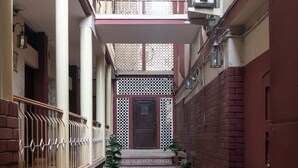 A narrow corridor with a tiled floor, a wooden railing on one side, and a staircase leading to a door with a decorative lattice. - Hotel Telehaus Lalbagh Botanical Garden (Bengaluru)