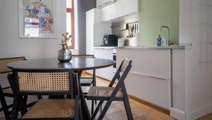 Una cocina moderna con armarios blancos, una mesa redonda de comedor con sillas de mimbre y un jarrón decorativo.