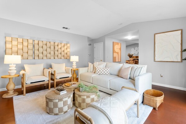 A modern living room with a sofa, armchairs, a coffee table, and a decorative wall panel.