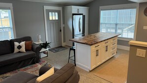 A modern kitchen with a central island, white cabinetry, and a refrigerator. There is a sofa and a small table with a lamp in the living area. -  The "Stable" at OGR!  5 Star Accommodations! 
Resort pool and spa!  Sleeps 4 (Holland)