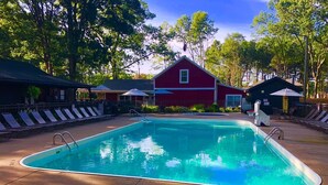 A swimming pool with lounge chairs and umbrellas, surrounded by trees and a red building. -  The "Stable" at OGR!  5 Star Accommodations! 
Resort pool and spa!  Sleeps 4 (Holland)