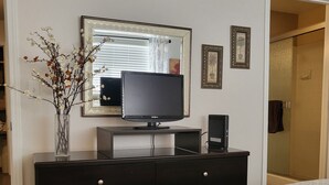 Une chambre à coucher avec un lit, une commode, un téléviseur et un miroir.