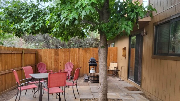 Une terrasse avec une table et des chaises, un barbecue et une clôture en bois.