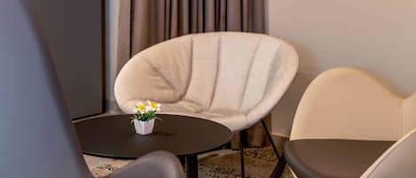 Una habitación moderna con una mesa redonda, dos sillas y una planta pequeña sobre la mesa.