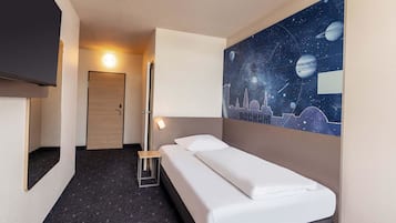 Ein Hotelzimmer mit Bett, Nachttisch, einem an der Wand befestigten Fernseher und einem Bild mit Weltraumdarstellung.