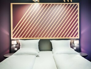 A hotel room with a large bed, two bedside tables with lamps, and a patterned wall above the bed. - B&B HOTEL Bochum Hbf-Nord (Bochum)