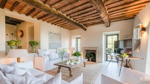 Un salon spacieux avec un haut plafond en bois, une cheminée et un téléviseur.