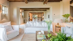 Un salon chaleureux avec un canapé blanc, une table basse agrémentée d’objets décoratifs et un plafond en bois.