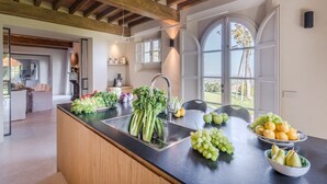 Une cuisine dotée d’un grand îlot central, d’un évier et offrant une vue sur l’extérieur.