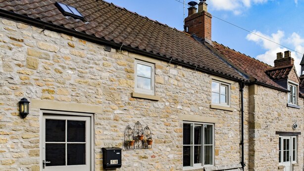 A stone building with a white door, a bench, and potted plants. - 2 bedroom accommodation in Helmsley (Helmsley)