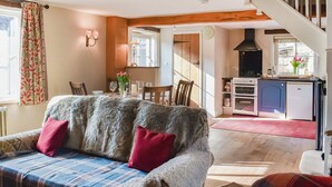 A cozy living room with a sofa, a dining area with chairs and a table, a kitchen with appliances, and a staircase. - 2 bedroom accommodation in Helmsley (Helmsley)