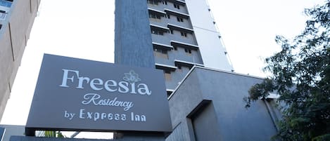 A tall building with a sign for Freesia Residency by Express Inn.