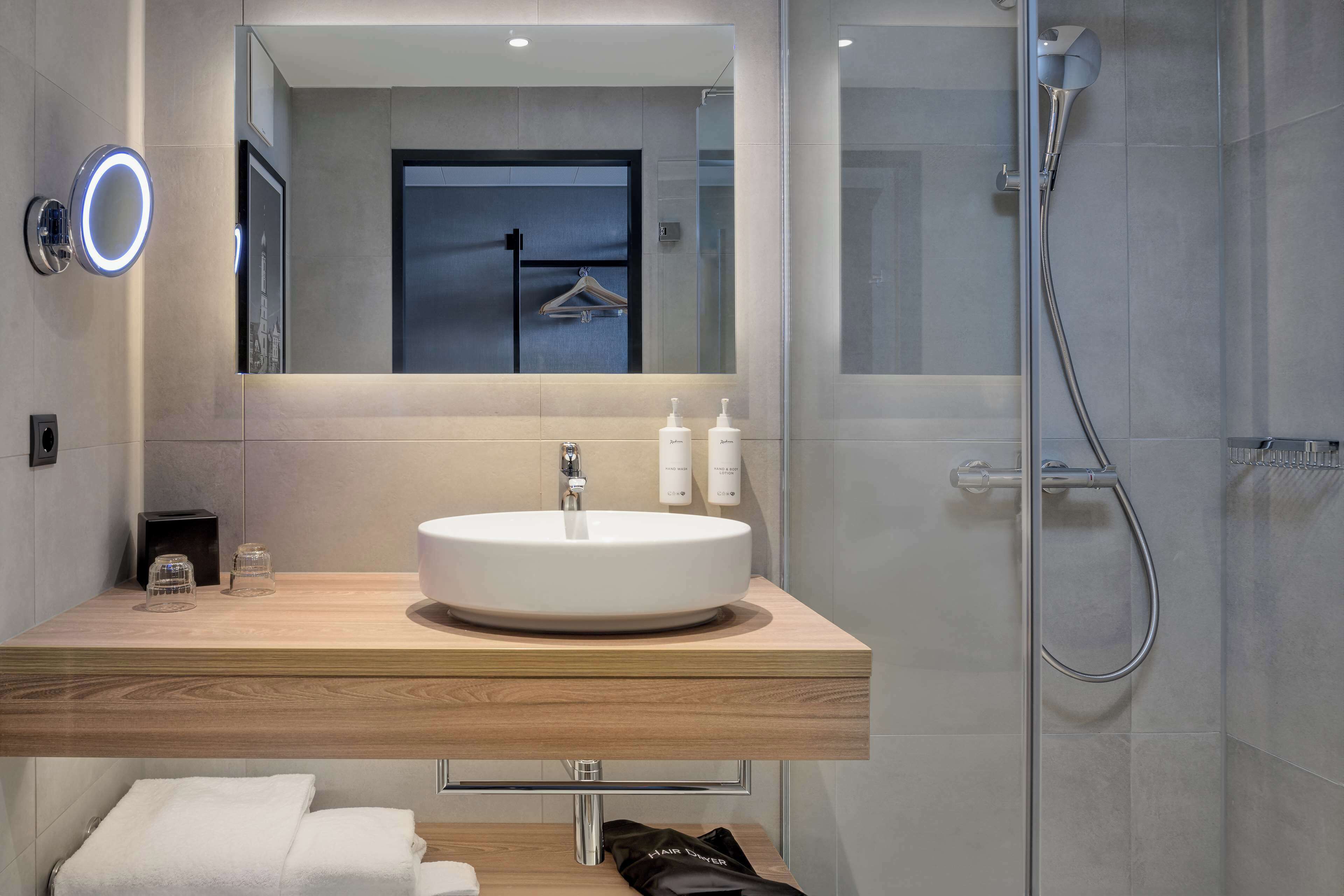 A modern bathroom with a round sink, a mirror, and a shower.