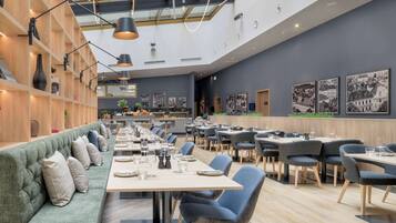 Un restaurante moderno con un amplio comedor, asientos acolchados y un techo alto con tragaluces.