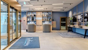 A modern reception area with a blue wall, wooden reception desk, and a sign that reads "Radisson."
