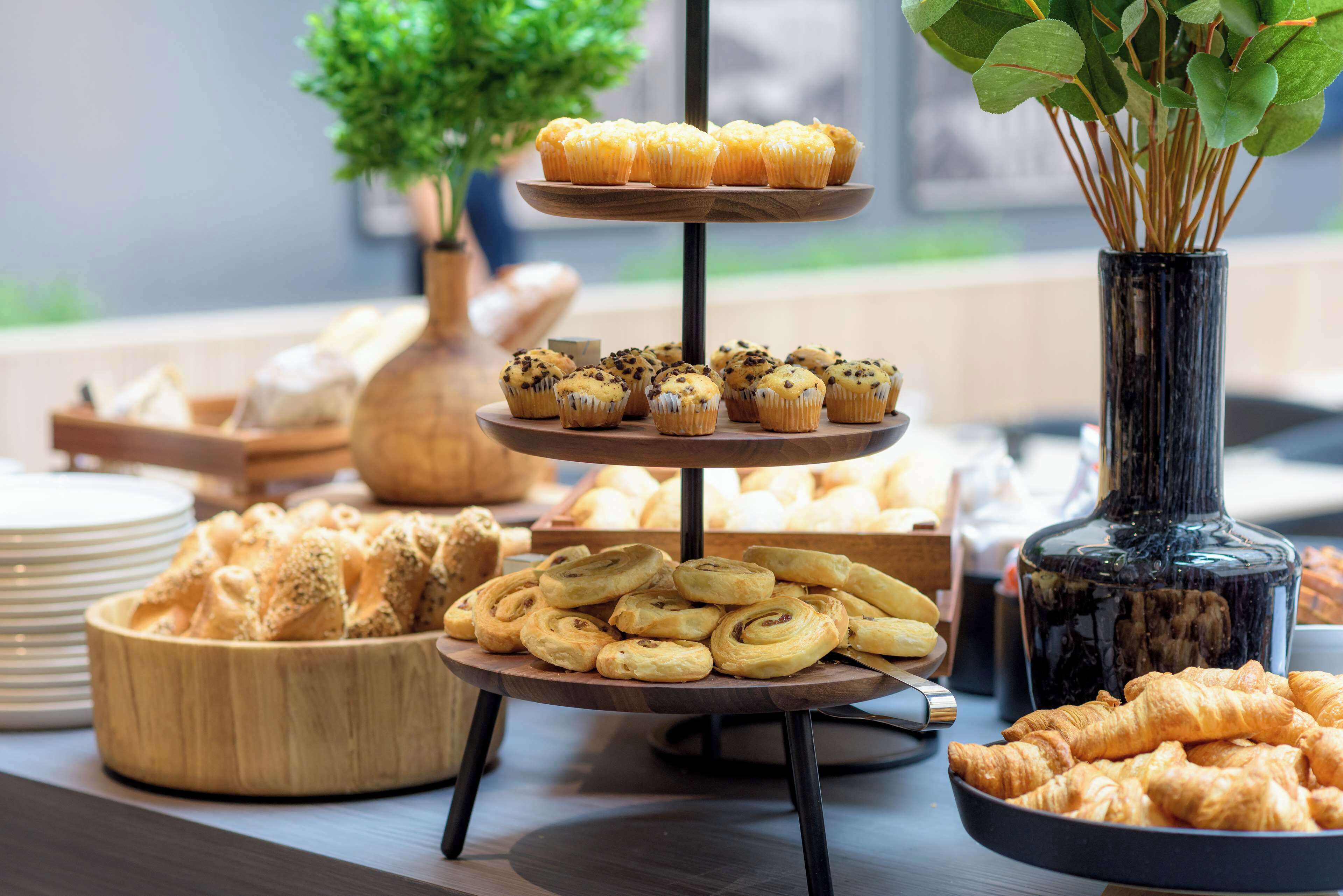 A buffet table with various baked goods including muffins, croissants, and pastries.