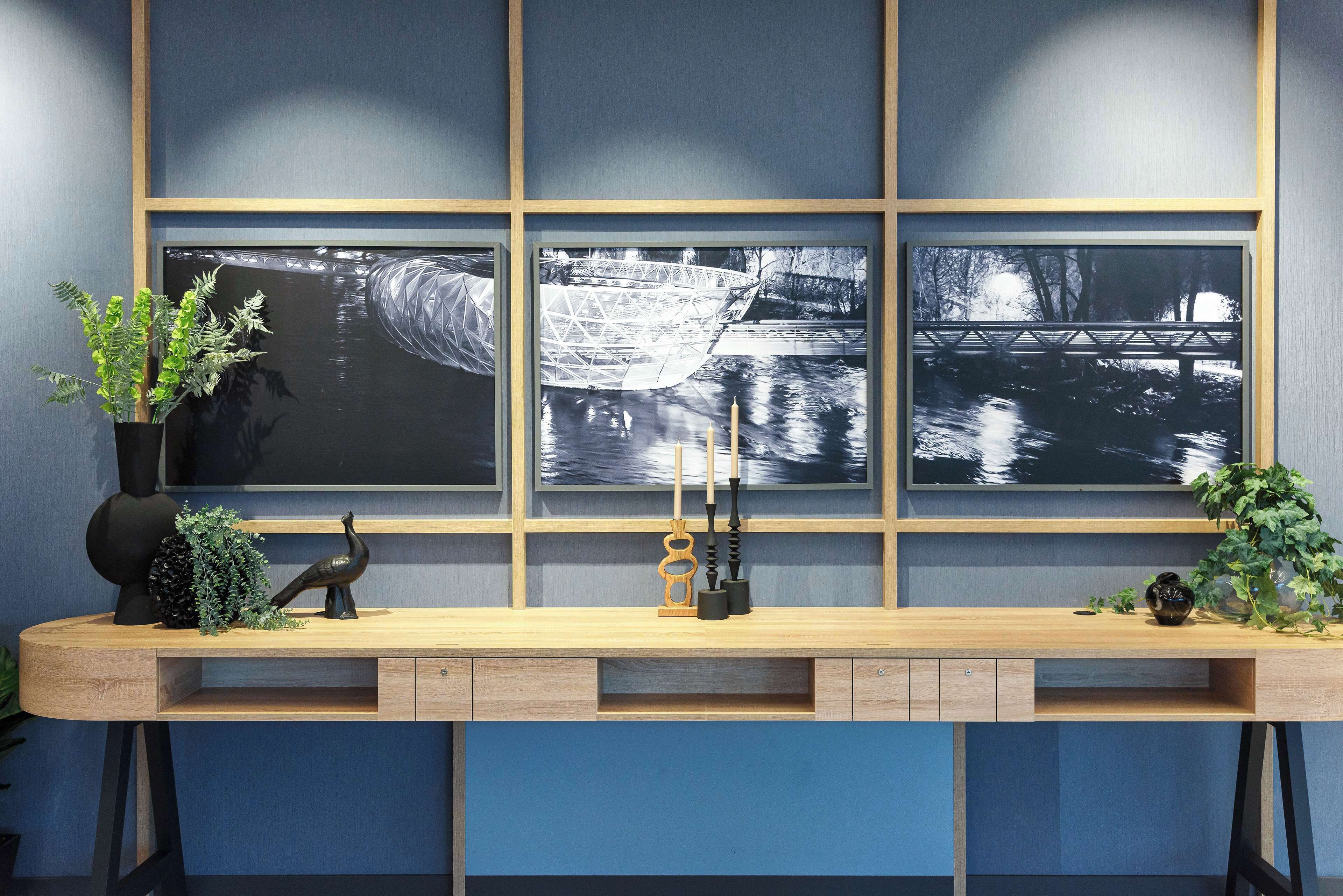 Un bureau moderne avec un placage en bois, un vase noir et une plante en pot.