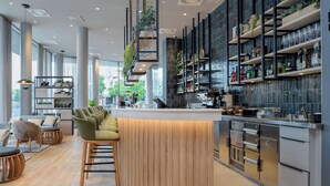 A modern bar area with a counter, bar stools, and shelves with bottles and glasses. - Radisson Hotel Graz (Graz)