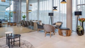 A modern hotel lobby with a glass wall, contemporary furniture, and large windows. - Radisson Hotel Graz (Graz)