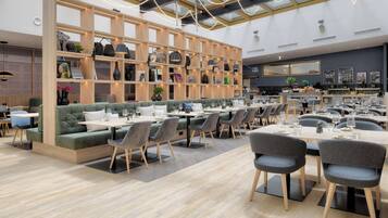A modern restaurant with wooden shelves, cushioned seating, and a variety of table settings.