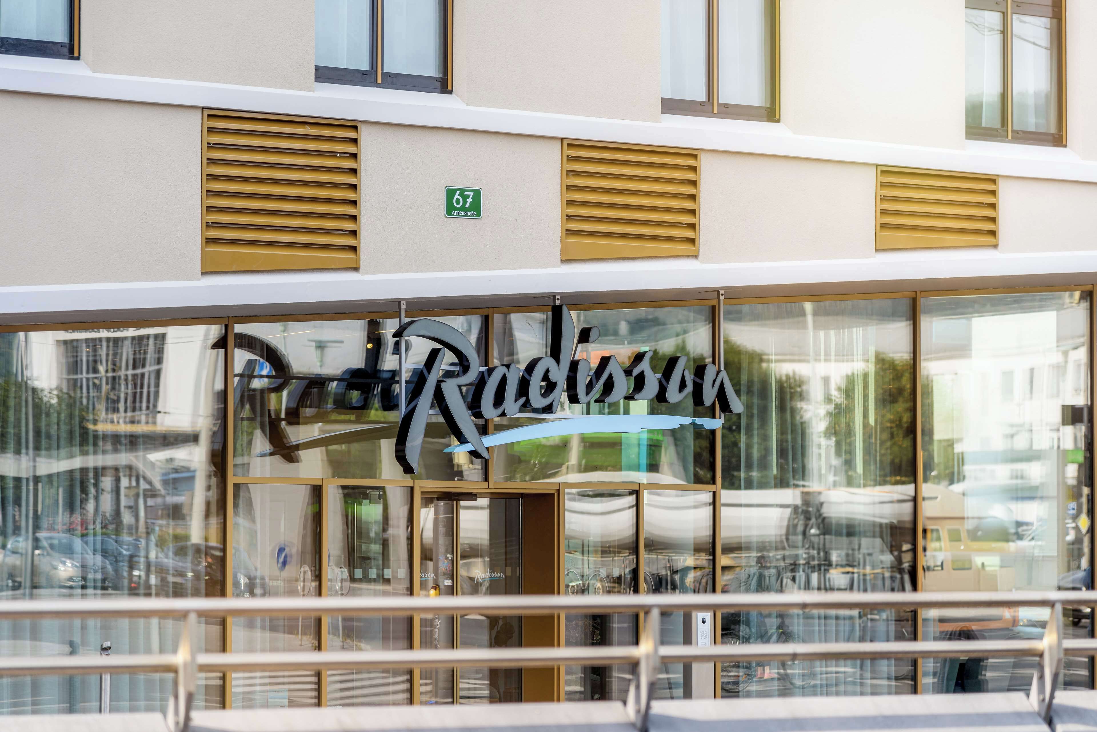A building with a large glass facade, a prominent sign reading "Racissu," and a green street sign indicating the address "67."