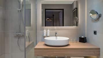 Une salle de bain moderne avec une douche à parois de verre, un lavabo rond et un miroir.