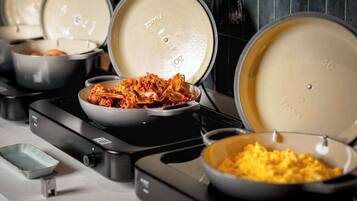 A kitchen with multiple pots on a stove, including a bowl of scrambled eggs and a dish of kimchi.