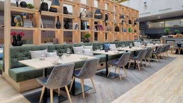 Un restaurante moderno con un amplio comedor, asientos acolchados y una selección de libros y objetos decorativos en estanterías.