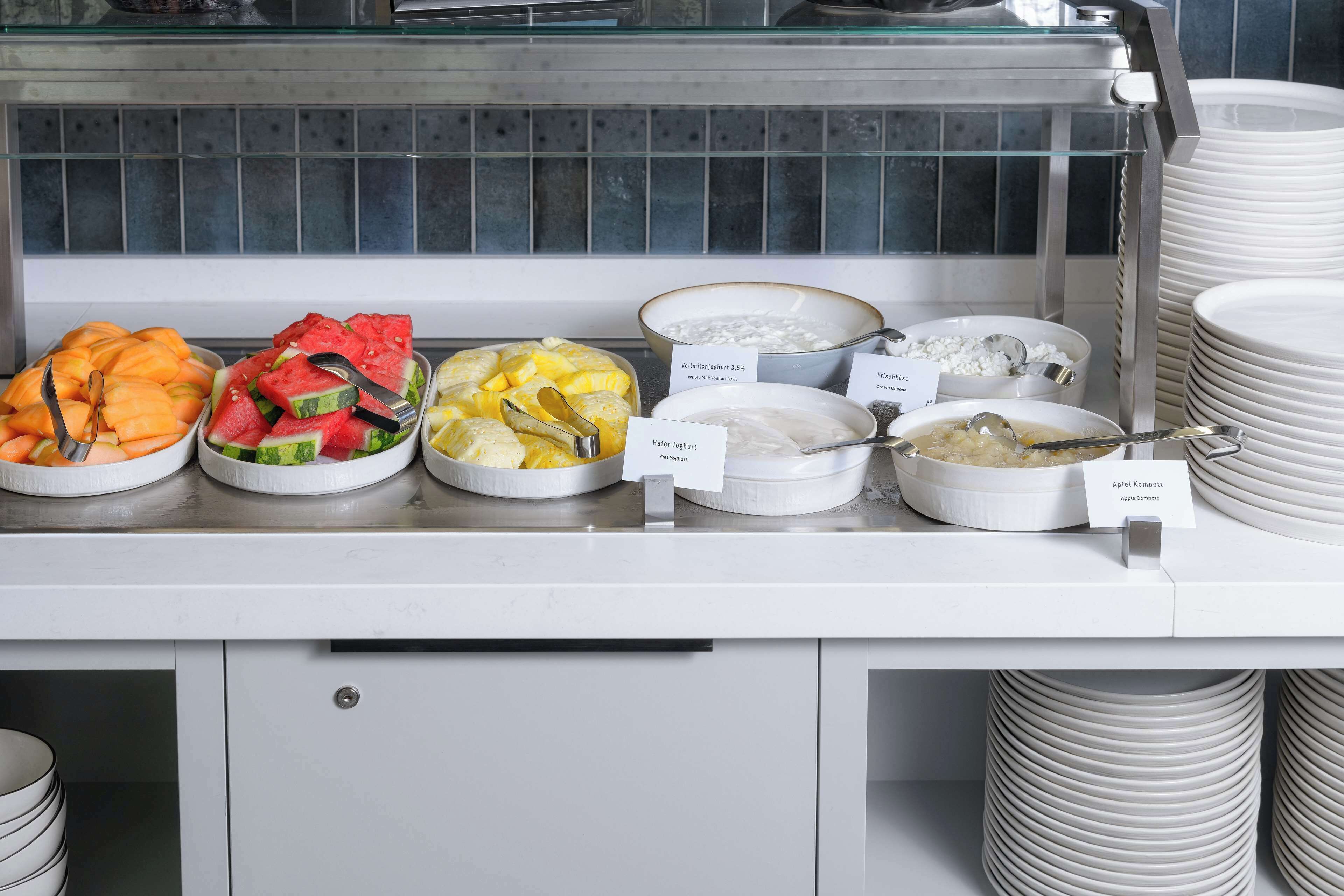A buffet counter with various food items and bowls labeled with their names.