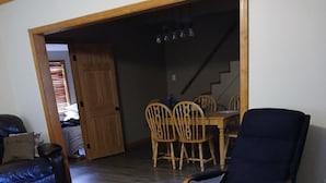 A living room with a wooden floor, a blue armchair, a sofa, and a dining area with wooden chairs and a table. - Newly renovated, only 2 miles from downtown Fort Kent.  Right across from trails (Fort Kent)