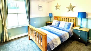 A bedroom with a wooden bed, two bedside tables with lamps, a star decoration on the wall, and a window with curtains.