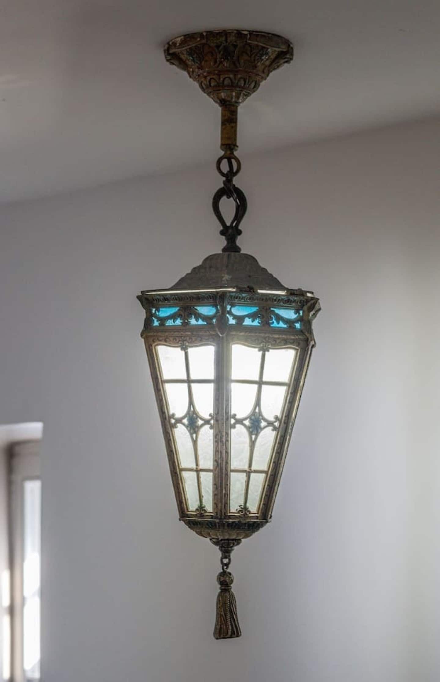 A hanging lantern with a decorative top and a tassel at the bottom.