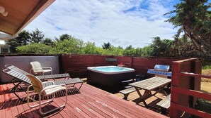 An outdoor deck with a hot tub, lounge chairs, and a grill. - Beachfront Cabin, Downtown, Hot Tub, Fully Fenced! (Ocean Shores)