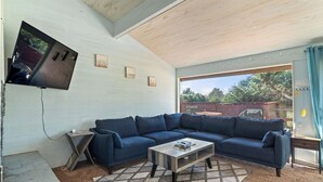 A modern living room with a sectional sofa, a coffee table, and a TV mounted on the wall. - Beachfront Cabin, Downtown, Hot Tub, Fully Fenced! (Ocean Shores)