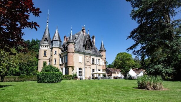 A large, historic building with multiple towers and a well-maintained lawn. - Château le Haget (Montesquiou)