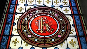 A stained glass window with a central circular design featuring a prominent letter 'L' and decorative elements. - Château le Haget (Montesquiou)
