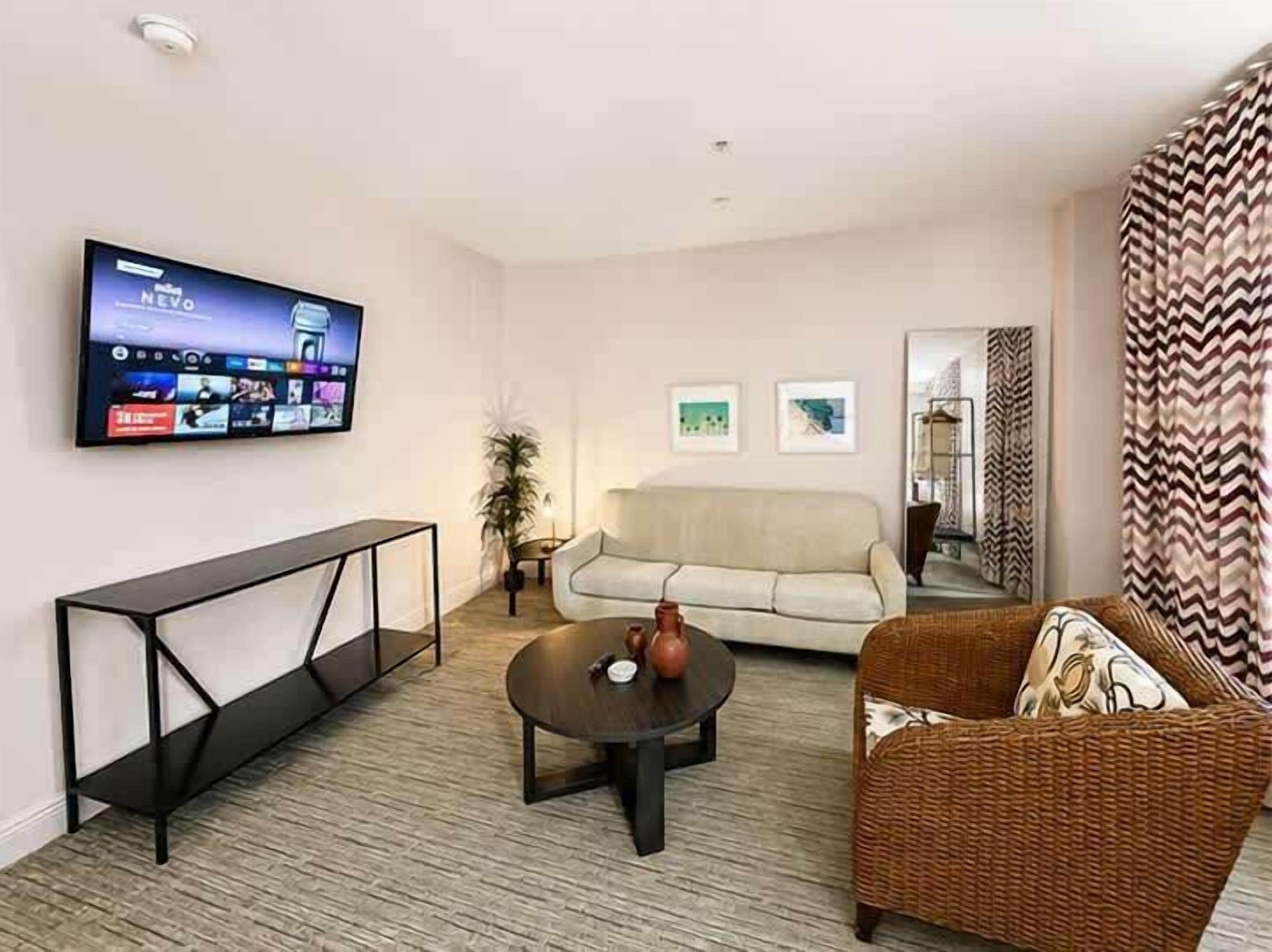 A living room with a flat-screen TV mounted on the wall, a sofa, a coffee table, and a console table.