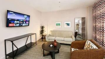 A living room with a flat-screen TV mounted on the wall, a sofa, a coffee table, and a console table.