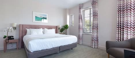 A bedroom with a bed, bedside table, lamp, and curtains.
