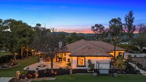 A house with a tiled roof, a patio with outdoor lighting, and a well-maintained lawn. - Breathtaking Meadows by Avantstay Temecula Group Retreat Pool, Pickleball, Firepit, Hot Tub (Temecula)