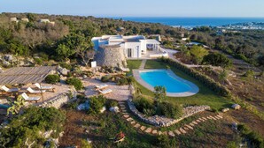 Une villa moderne dotée d’une piscine, entourée d’un jardin aménagé et offrant une vue sur la côte.