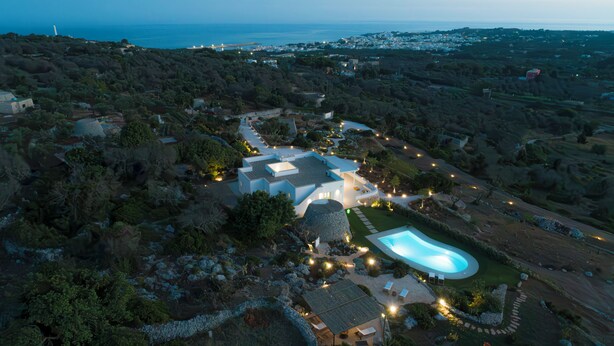 Vue aérienne d’un complexe hôtelier moderne doté d’une piscine, de jardins aménagés et offrant une vue sur la côte.